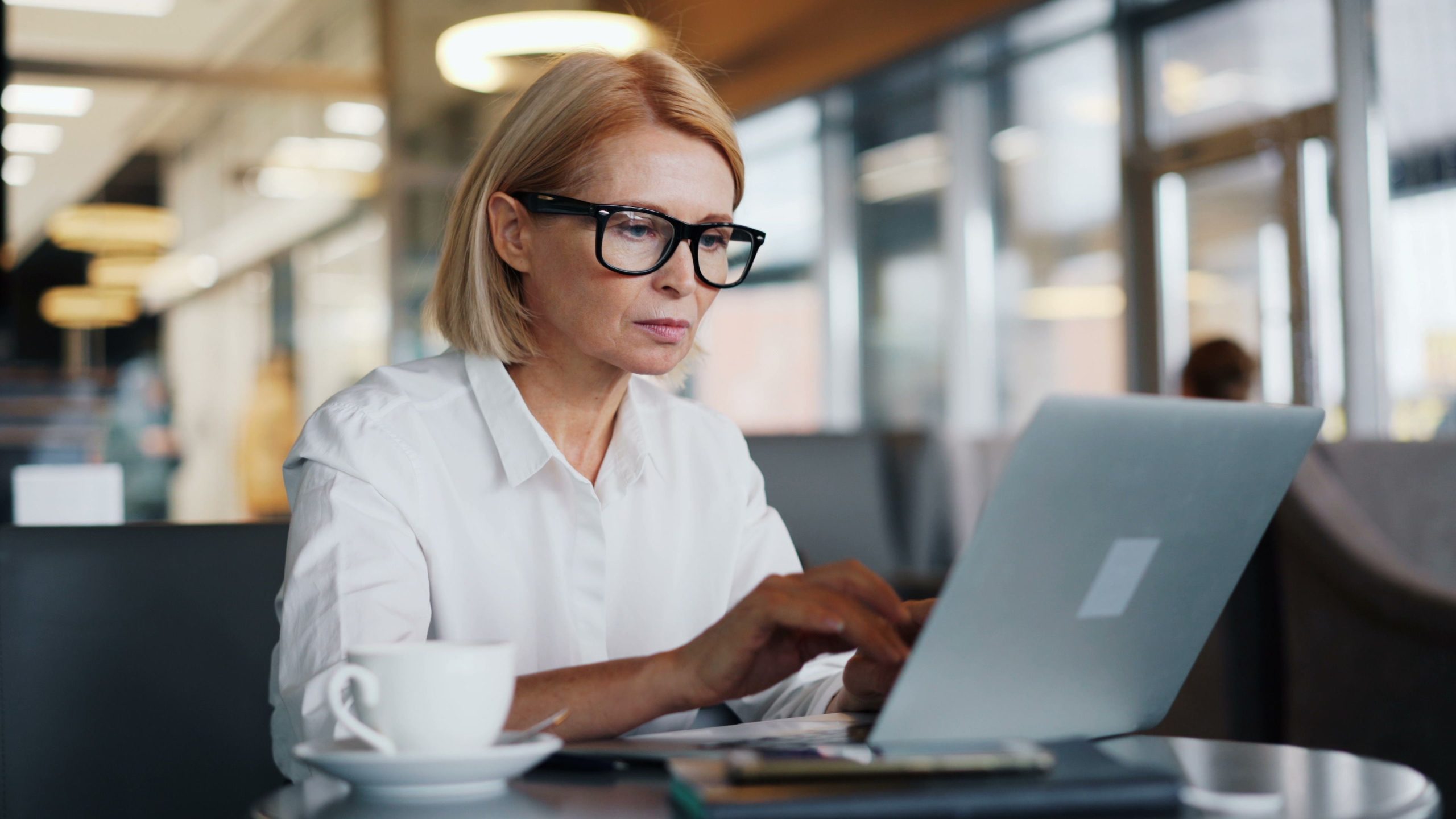 Femme avec lunettes utilisant son ordinateur portable au café