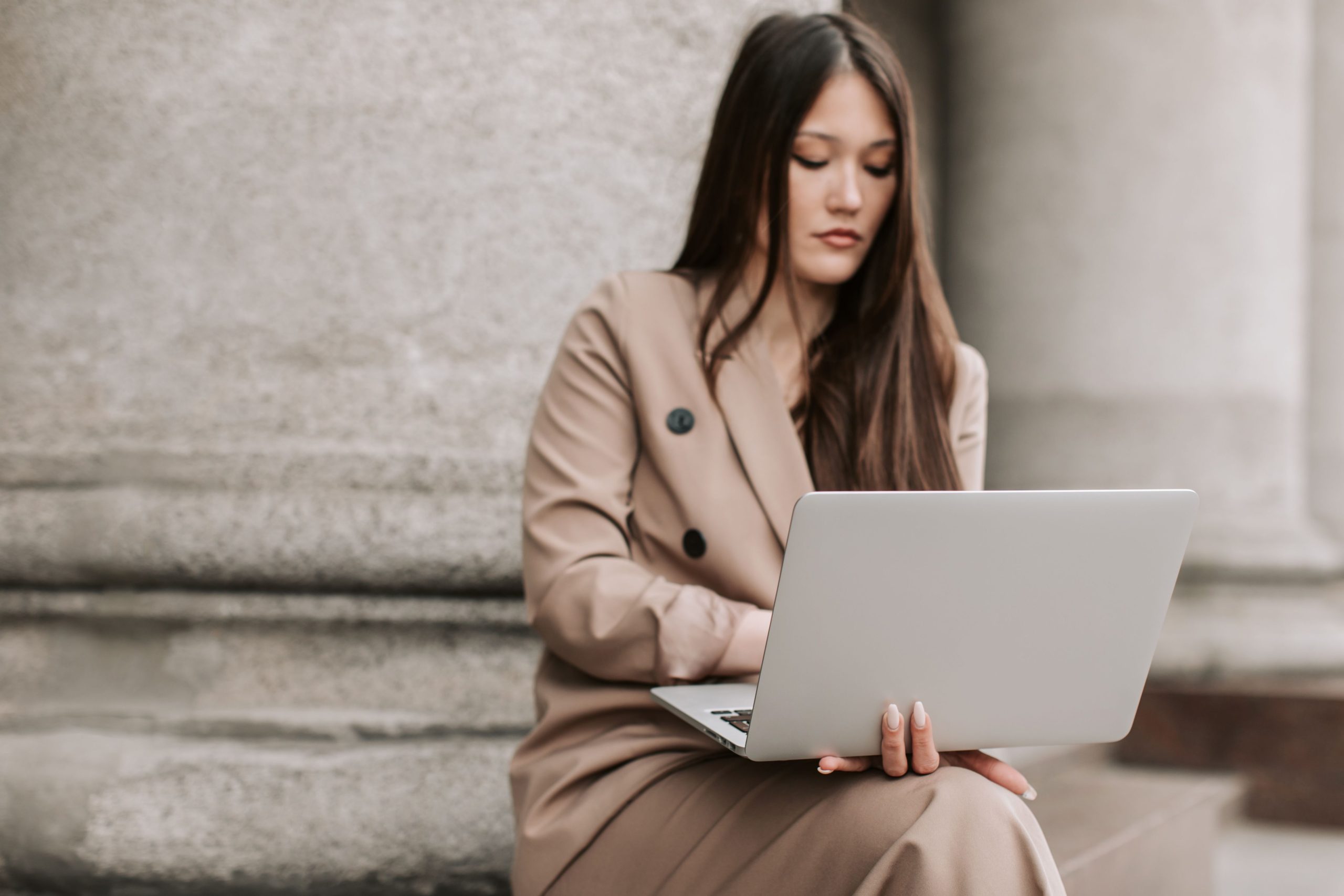 Femme en veste travaillant sur ordinateur devant un bâtiment